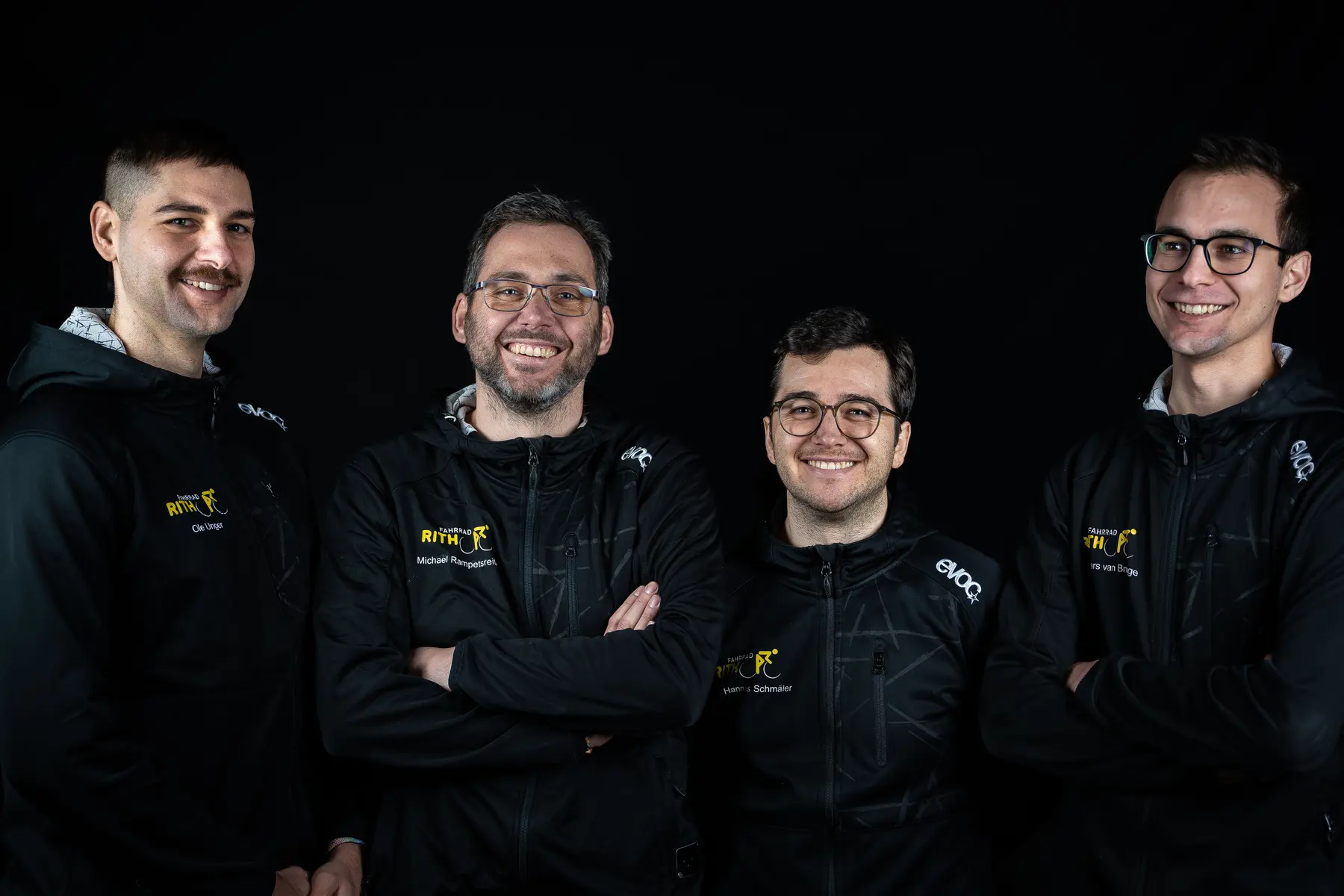 Das Team von Fahrrad Rith in Teamjacken vor schwarzem Hintergrund